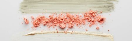 Top view of cosmetic clay and tone cream brushstrokes with blusher on grey background, panoramic...