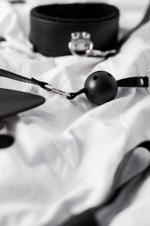 selective focus of gag near bdsm leash on white beddingの写真素材