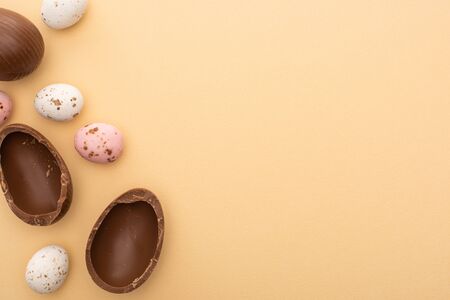 Top view of colorful quail and chocolate eggs on beige background