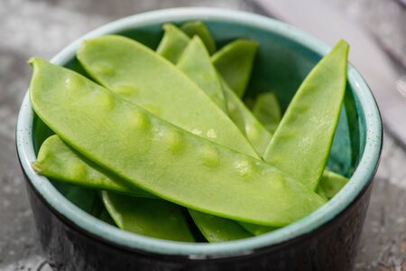 close up view of fresh green pea in bowl on grey concrete surfaceの写真素材