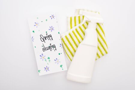 top view of cleaning supplies near spring cleaning card on white background