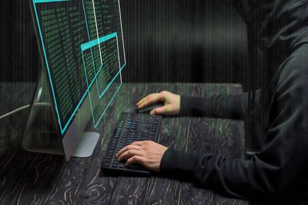 cropped view of hacker typing on computer keyboard near computer monitor with data on black