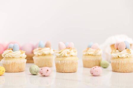 Selective focus of easter cupcakes with painted quail eggs on grey background