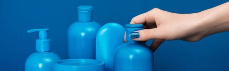 panoramic shot of woman holding bottle with shampoo on blue backgroundの写真素材