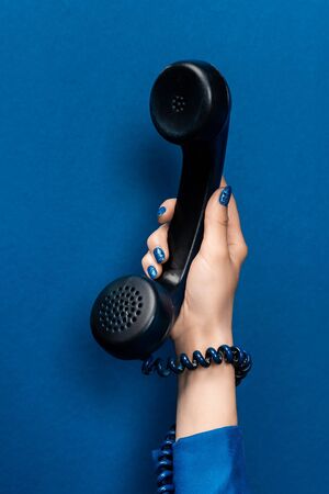 cropped view of woman holding handset on blue backgroundの写真素材