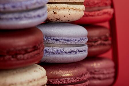 stack of assorted delicious colorful french macaroons on red backgroundの写真素材