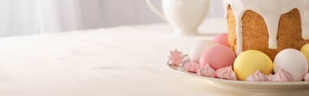 delicious Easter cake near meringue with pink and white eggs on plate, panoramic shot