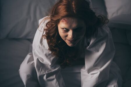 overhead view of demoniacal smiling woman in nightgown sitting in bedの写真素材