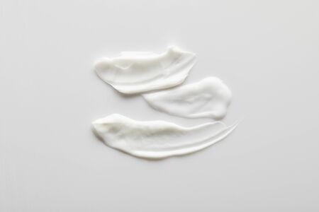 Top view of cosmetic cream brushstrokes on grey