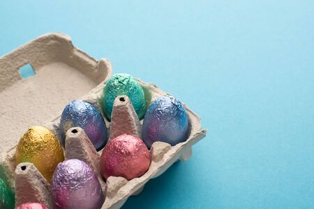 Chocolate easter eggs in egg tray on blue background