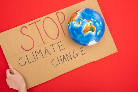 Cropped view of woman holding placard with stop climate change lettering and globe on red, global warming conceptの写真素材