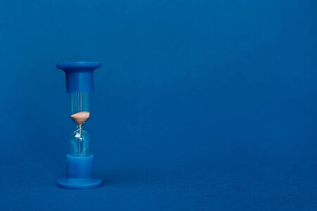 bright and colorful hourglass on blue background with copy space
