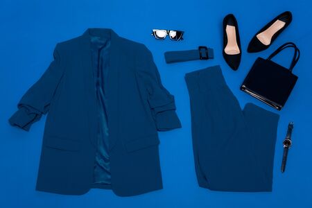 top view of jacket, trousers, heels, belt, bag, wristwatch and sunglasses isolated on blueの写真素材
