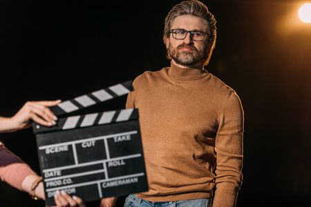 selective focus of mature actor with clapboard in front