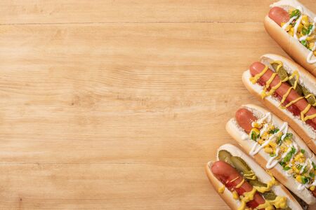 top view of delicious hot dogs with corn, green onion and pickles on wooden tableの写真素材