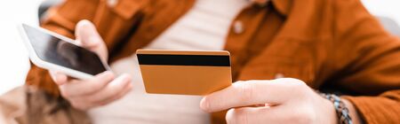 Cropped view of 3d artist holding credit card and smartphone isolated on white, panoramic shot