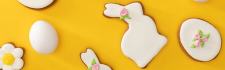 Top view of tasty easter cookies and chicken egg on yellow background, panoramic shotの写真素材
