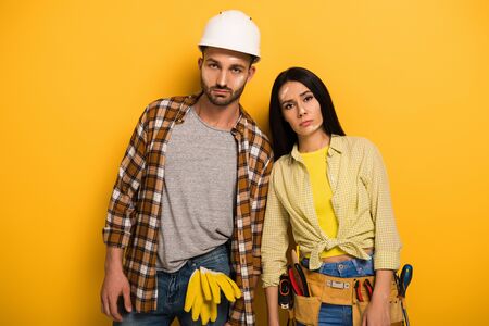 sad tired manual workers standing on yellowの写真素材