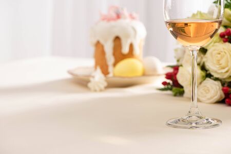 selective focus of delicious Easter cake with eggs on plate near flowers and wine