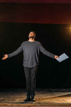 emotional african american actor holding scenario on stage during rehearseの写真素材