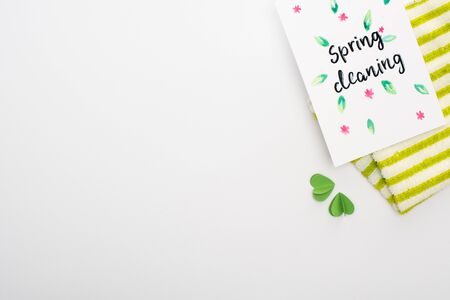 top view of green rag with hearts near spring cleaning card on white background