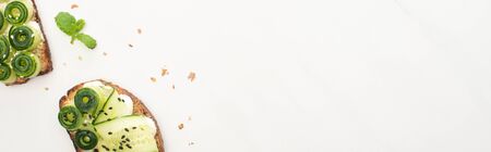 top view of fresh cucumber toasts with seeds, mint on white background, panoramic shot