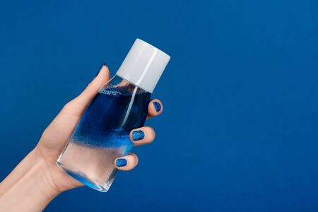 cropped view of woman holding micellar cleansing water isolated on blueの写真素材
