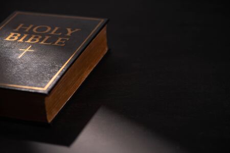 holy bible on black dark background with sunlight