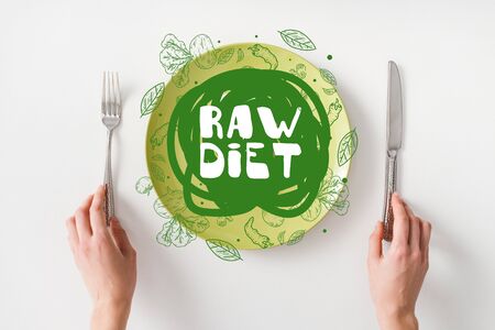 Top view of woman holding cutlery near smartphone on green plate on white backgroundの写真素材