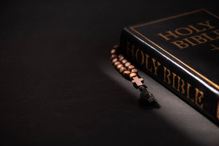 holy bible with rosary on black dark background with burning candlesの写真素材