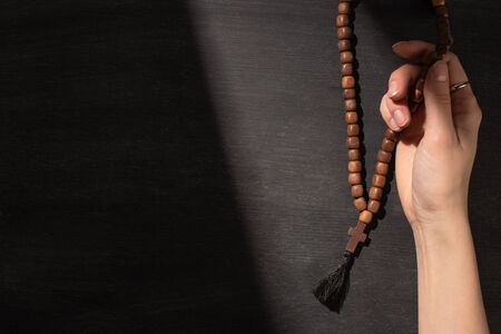 cropped view of woman praying with rosary on dark backgroundの写真素材