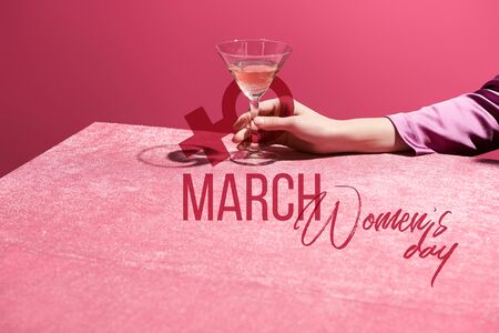 cropped view of woman holding glass of rose wine on velour cloth isolated on pink, 8 march illustrationの写真素材