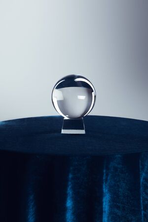 Crystal ball on round table with dark blue tablecloth on grey backgroundの写真素材