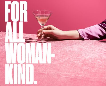 cropped view of woman holding glass of rose wine on velour cloth isolated on pink, for all woman kind illustrationの写真素材