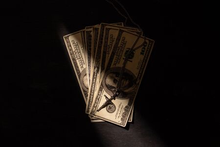 top view of money and cross on dark background with sunlightの写真素材