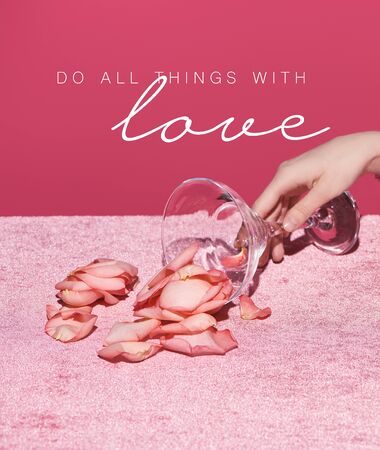 cropped view of woman with scattered petals from glass on velour cloth isolated on pink, do all thing with love illustrationの写真素材