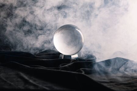 Crystal ball on textile with smoke on dark backgroundの写真素材