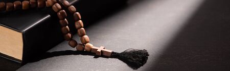 holy bible with rosary on black dark background with sunlight, panoramic shotの写真素材