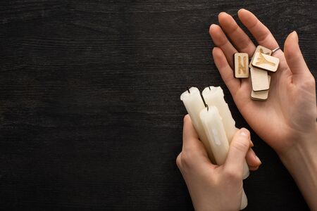 Top view of shaman holding runes ans candles near dark wooden backgroundの写真素材