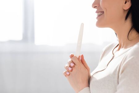 cropped view of cheerful woman holding pregnancy testの写真素材