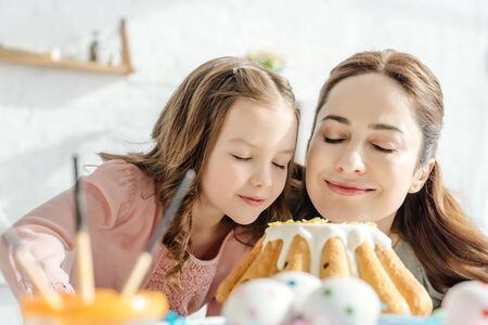 selective focus of happy mother and daughter smelling easter cakeの写真素材