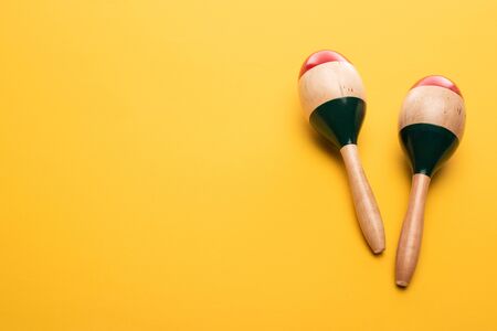 Top view of wooden maracas on yellow background