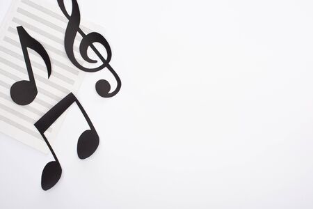 Top view of paper cut black notes on music book on white background