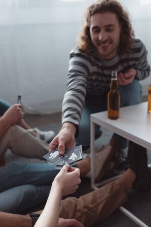 KYIV, UKRAINE - JANUARY 27, 2020: cheerful man taking card while playing mafia game with friendsの写真素材