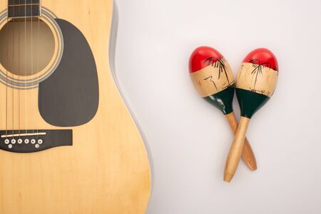 Top view of acoustic guitar near wooden maracas on whiteの写真素材