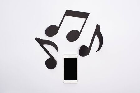 Top view of music paper cut notes and smartphone on white background
