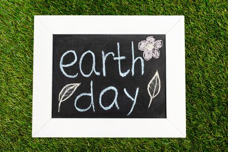 Top view of board with earth day lettering on greenの写真素材