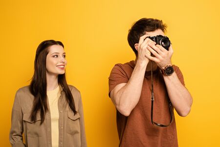 couple of happy tourists taking photo on photo camera on yellow