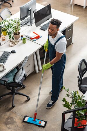 high angle view of african american cleaner washing floor with mop in officeの写真素材