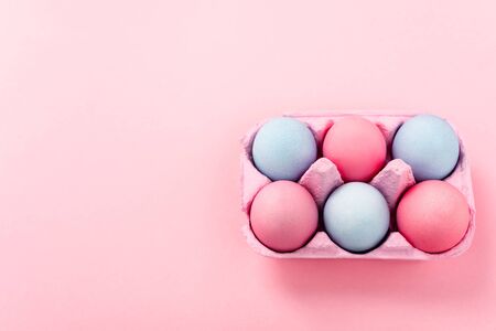 High angle view of painted easter eggs in egg tray on pinkの写真素材